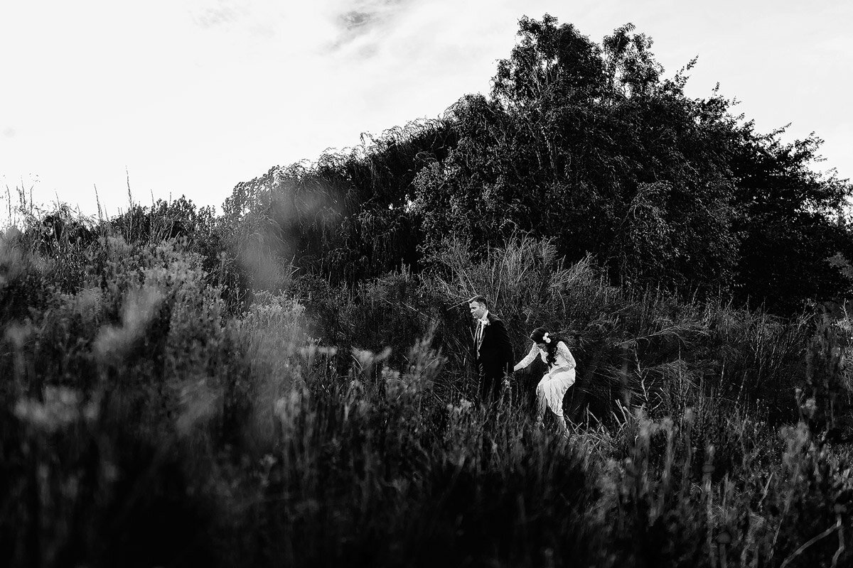 Bride and Groom walking in nature and fynbos on their Wedding Day.