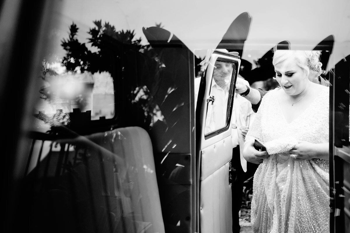 A bride entering her VW Kombi transport en route to her wedding ceremony.