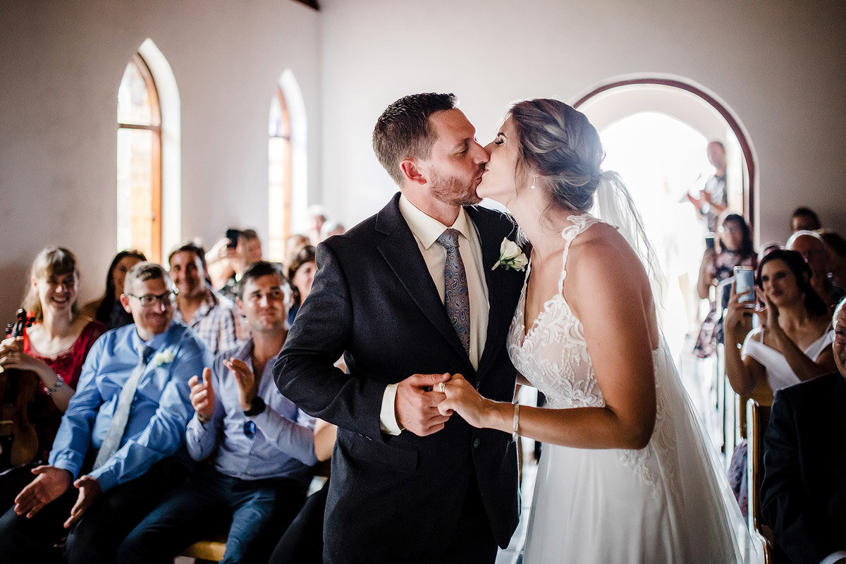 A wedding kiss between bride and groom in the small wedding chapel at Ballots Bay near George.