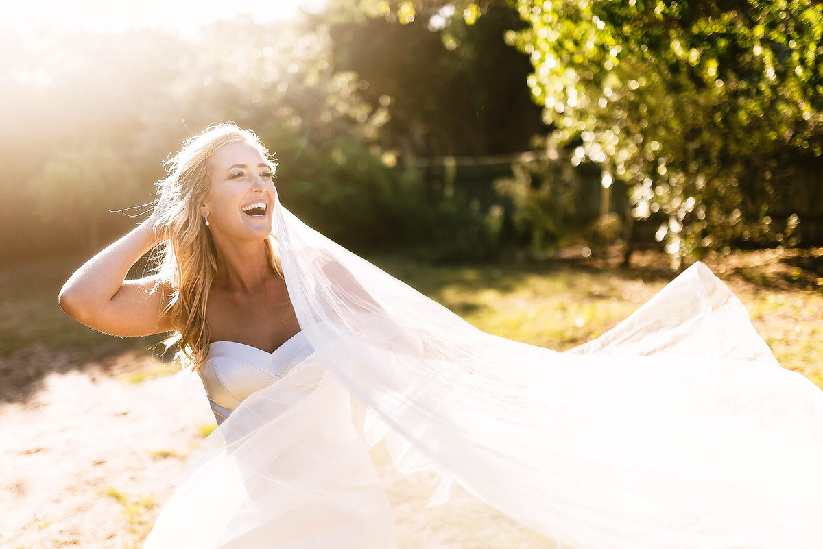 Funny moment bridal portrait with veil blowing in the wind.