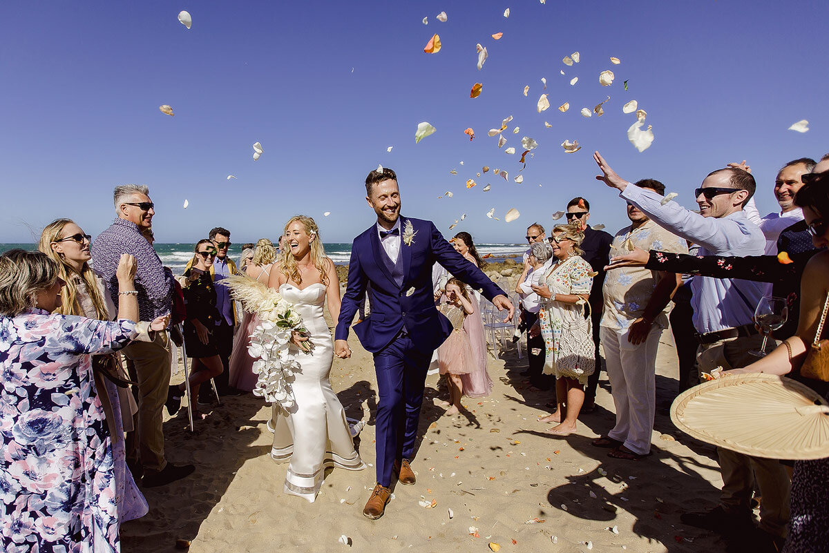Bride and groom walking out to showers of confetti at their Garden Route Beach Wedding.