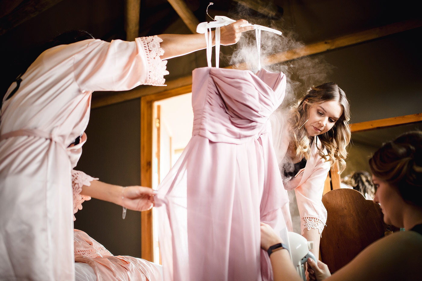 Bridesmaids steaming their wedding dresses before the ceremony starts.