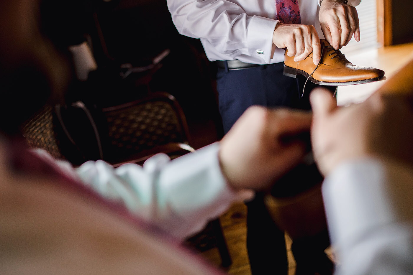 Groom putting on his wedding shoes.