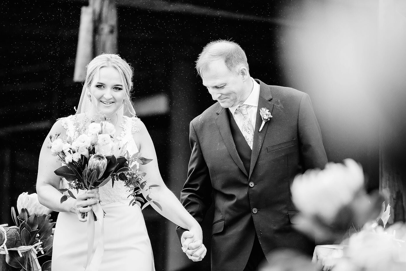 Bride walking  down the aisle with her father in the rain.