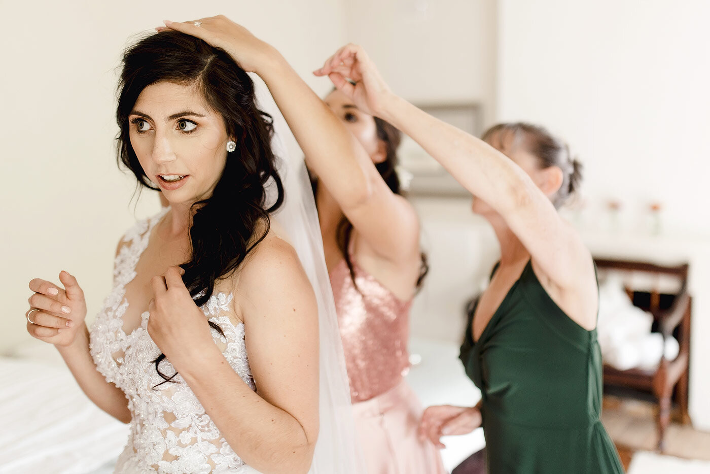 Mother and maid of honour helping the bride with her veil.