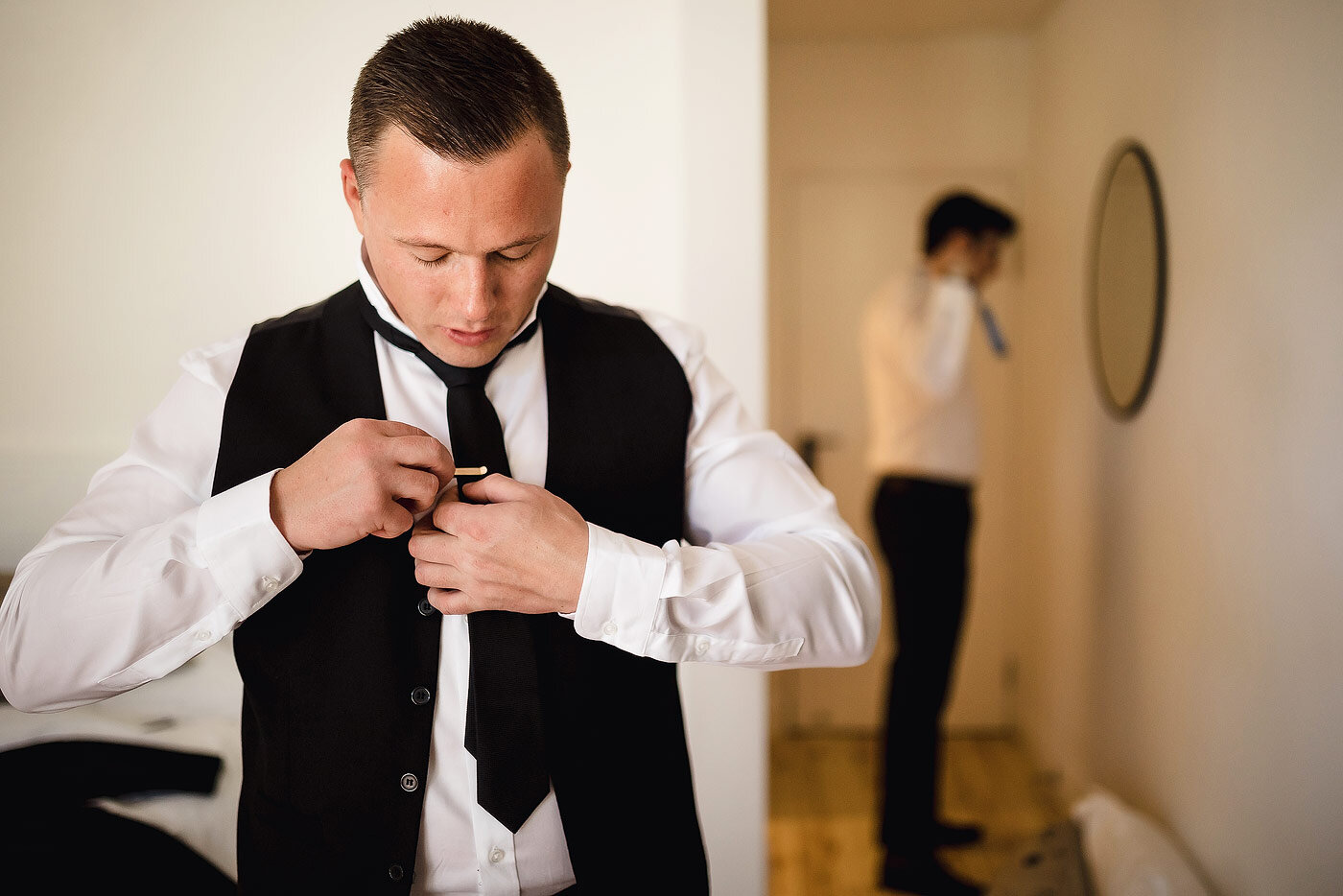 Creative portrait of a groom adjusting his tie.