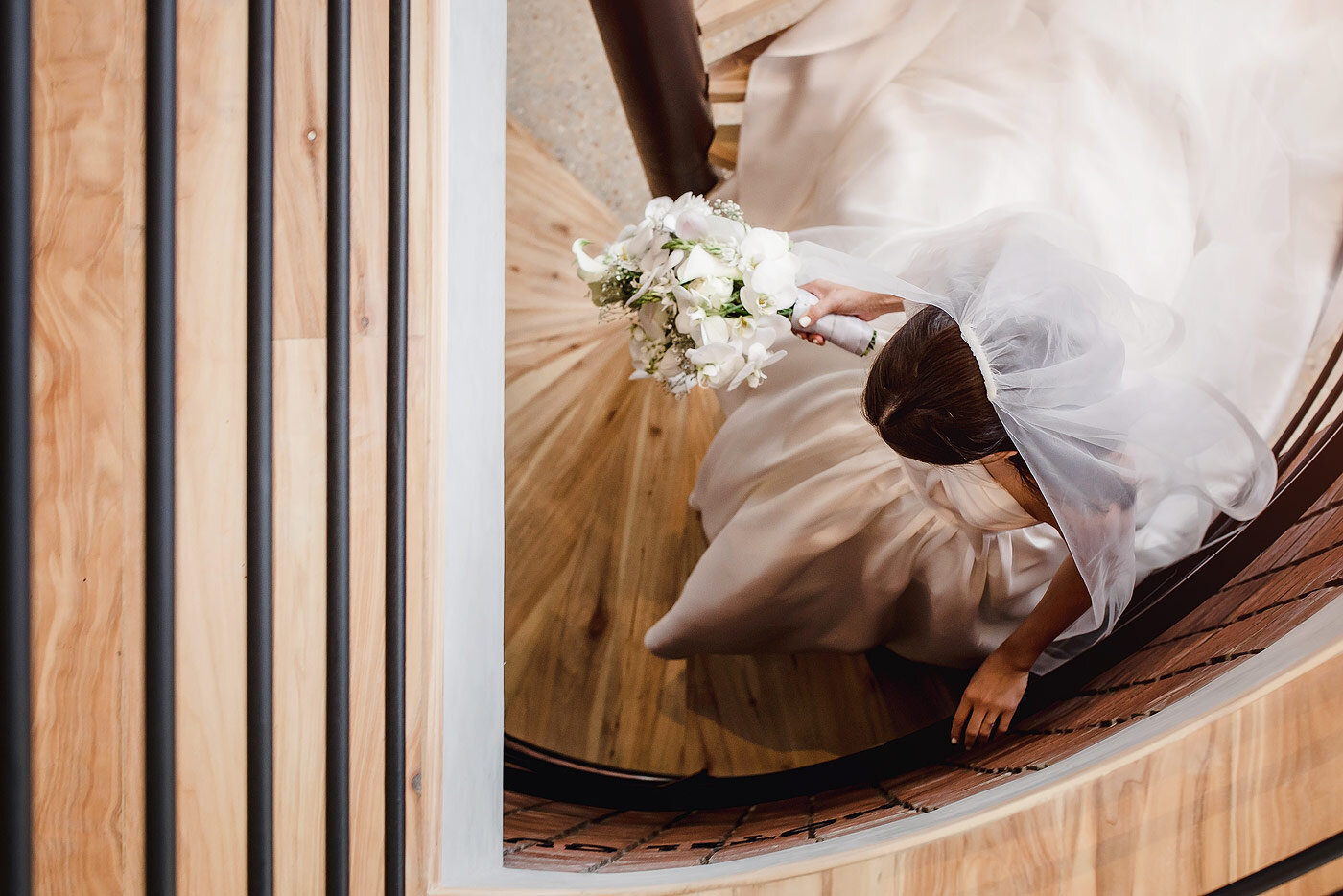 Bride walking down the stairs with a flowing veil.
