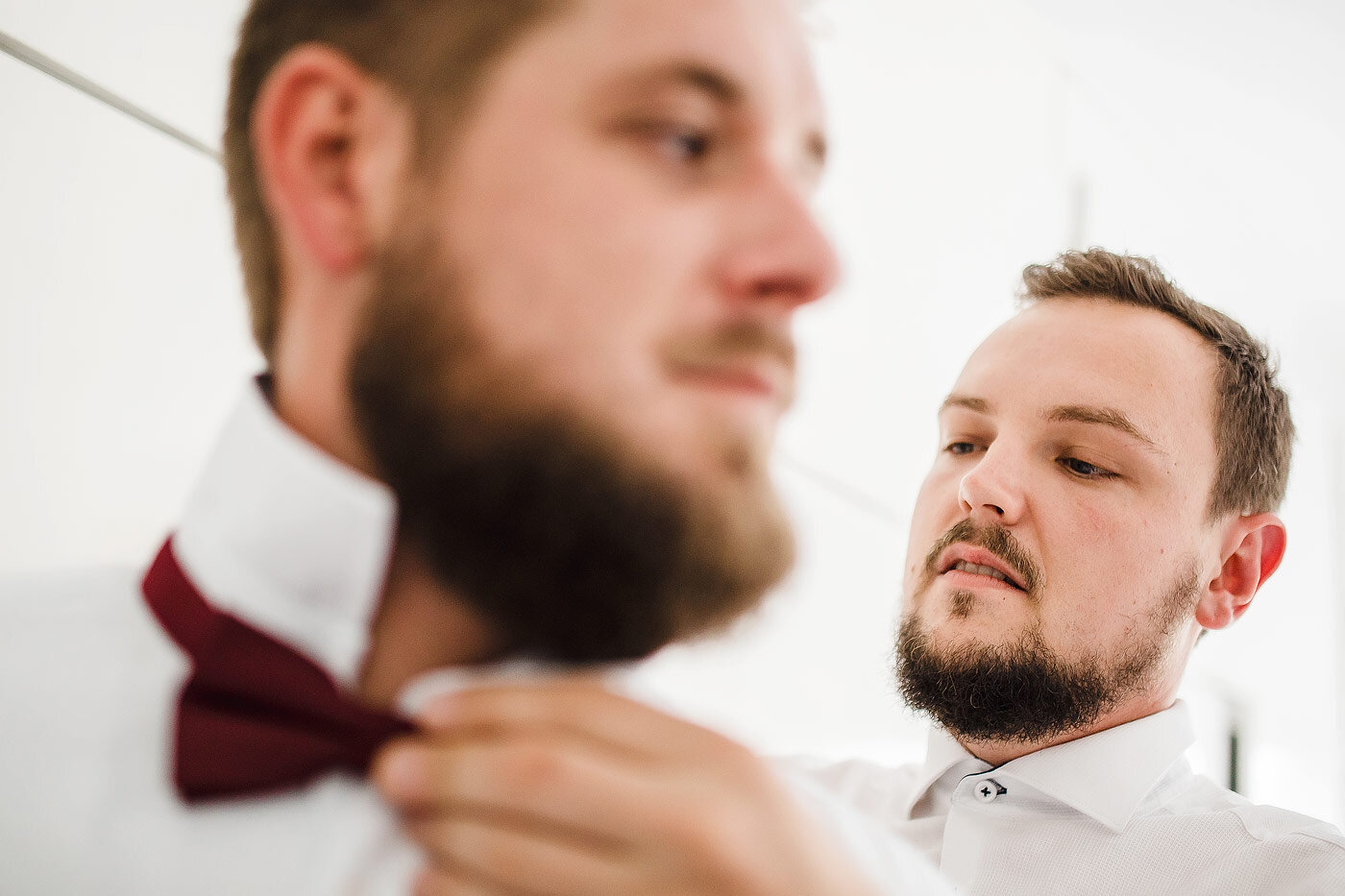 Groom adjusting a groomsmen bow-tie.
