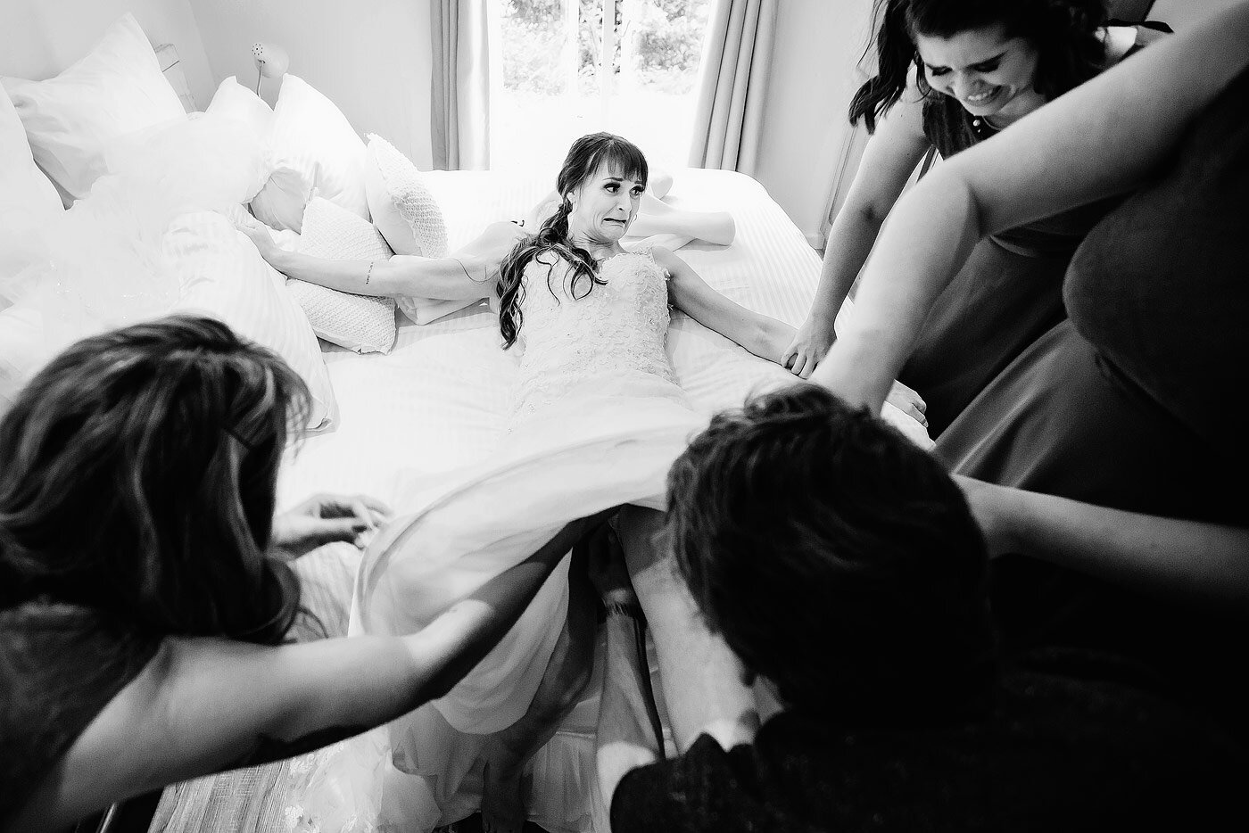 Bridesmaids helping the bride getting dressed in her wedding gown.