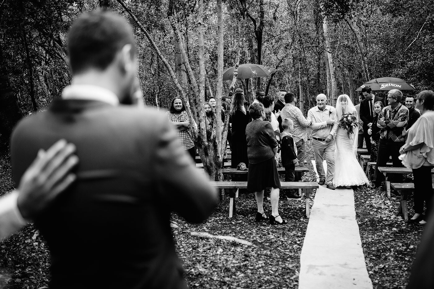 Bride walking down the aisle during her forest wedding celebration.