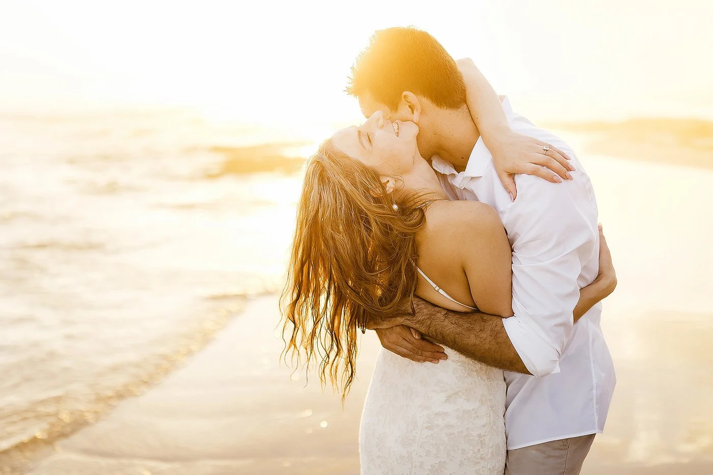 A couple embrace at sunset on the beach.