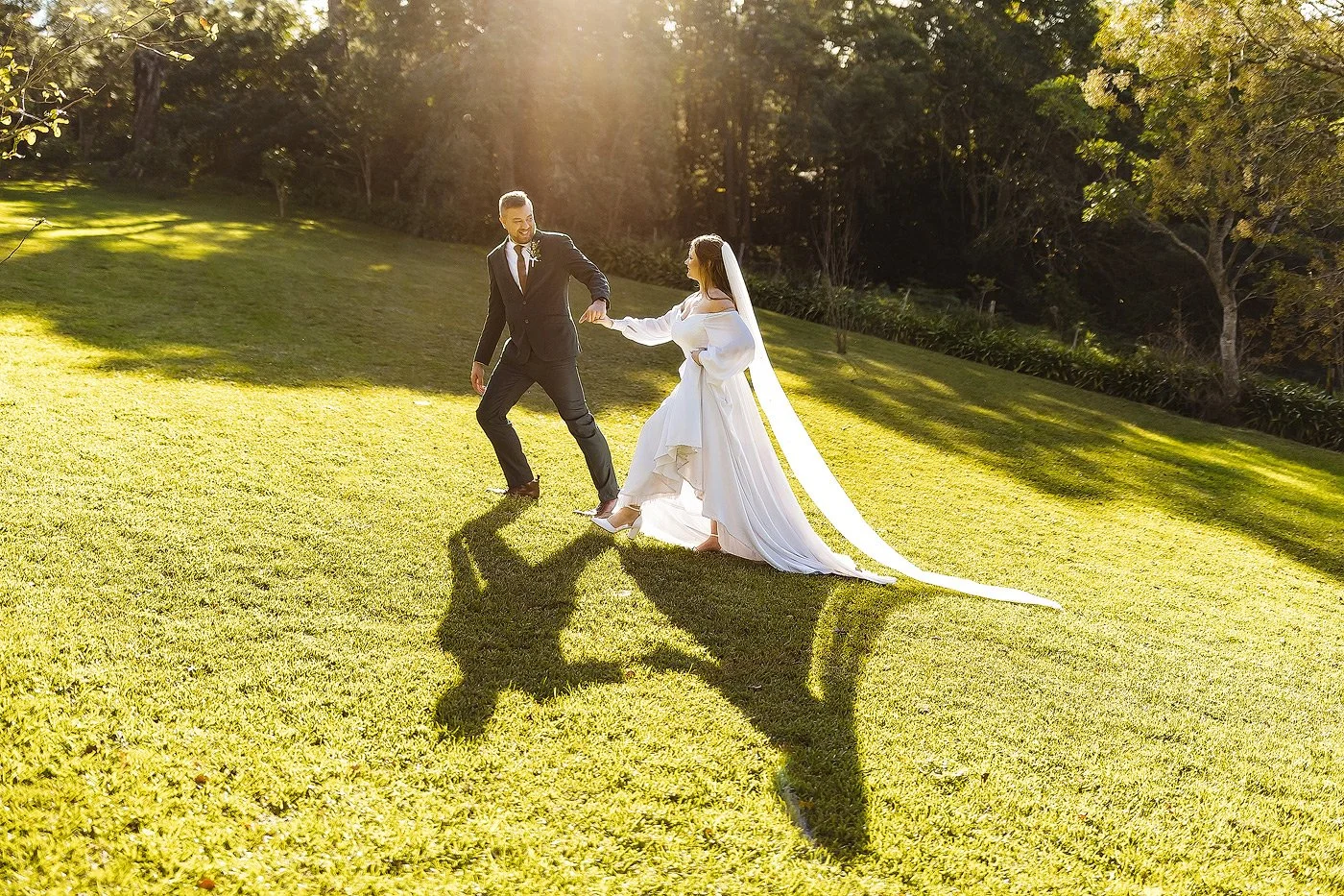Wedding Couple walking on a grass hill with backlit sun near Mossel Bay in the Garden Route.