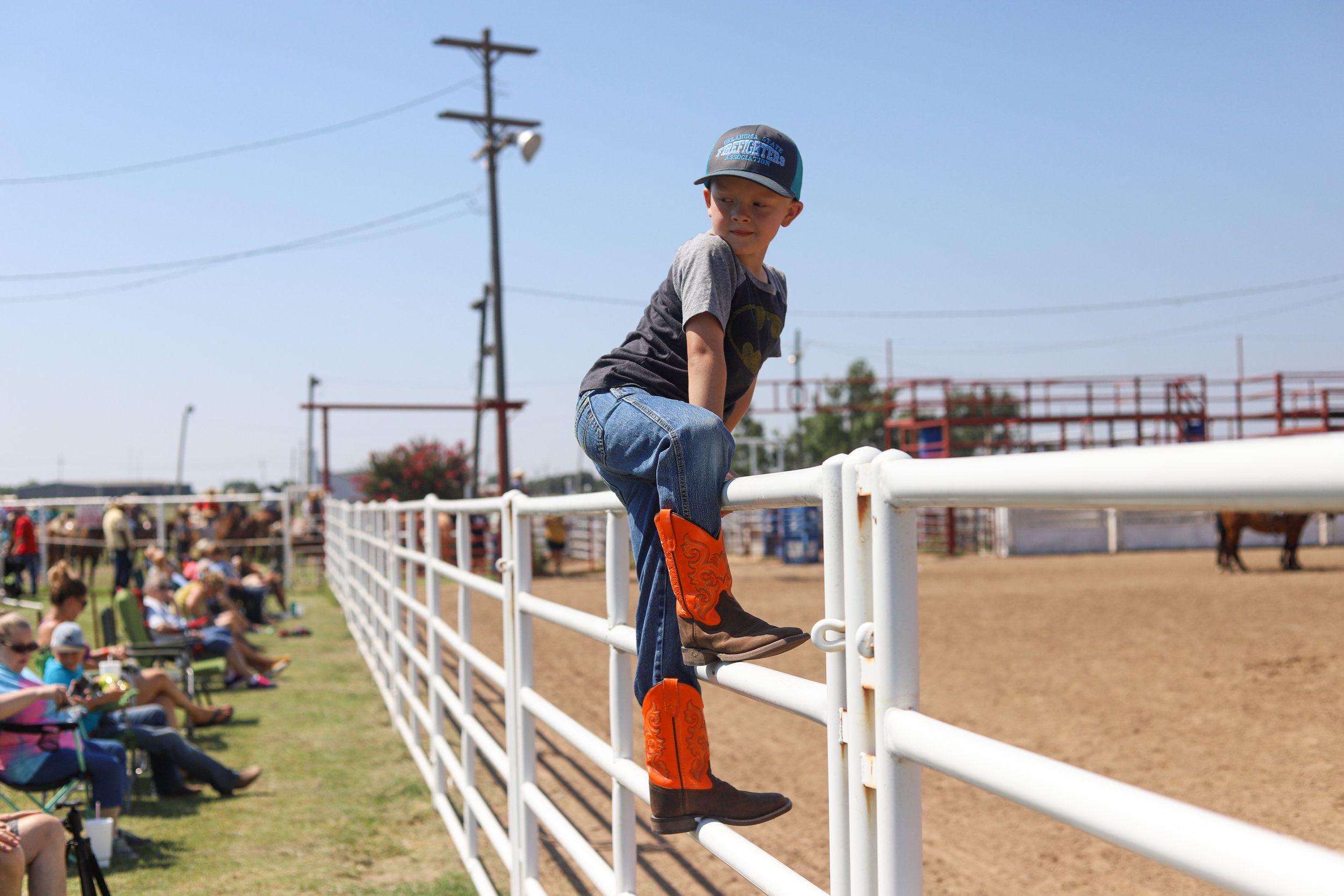 A young boy climbs on a fence to watch a cattle roping event during the youth ranch rodeo at the 101 Arena in Ponca City, Oklahoma.