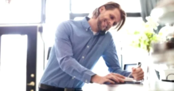 young-man-smiling-filling-out-book-at-hotel-desk-getty_573x300.jpg