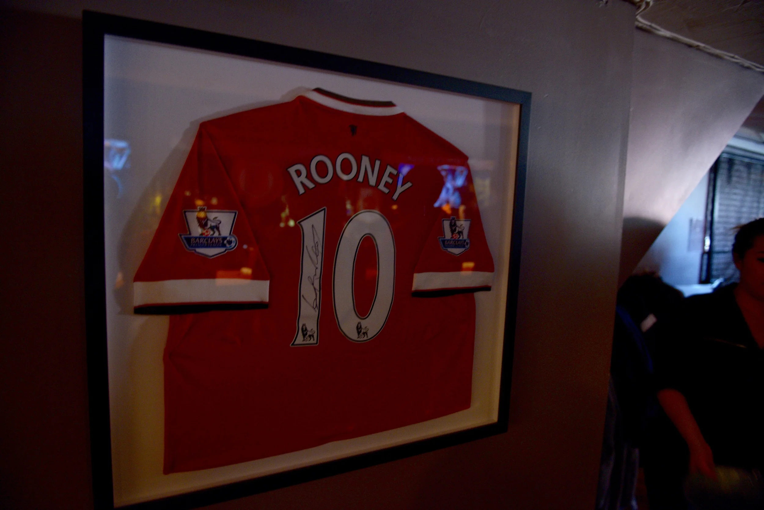A signed Wayne Rooney jersey hangs on the wall of Crossroads Irish Pub. Rooney has played for the club for 12 years, scored over 260 goals, and won 12 trophies with the club