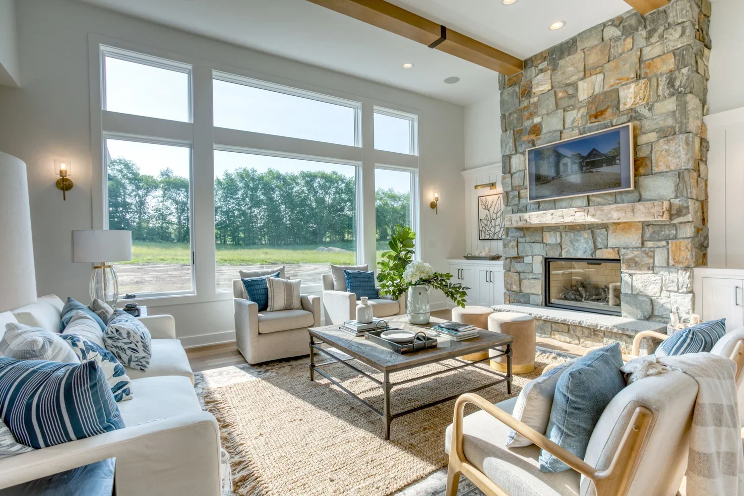 Custom home great room with floor to ceiling stone fireplace and exposed beam built by Celebrity Builders in West Michigan
