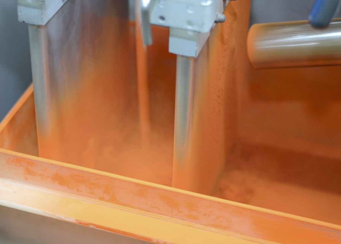 Sheets of metal being sprayed bright orange.