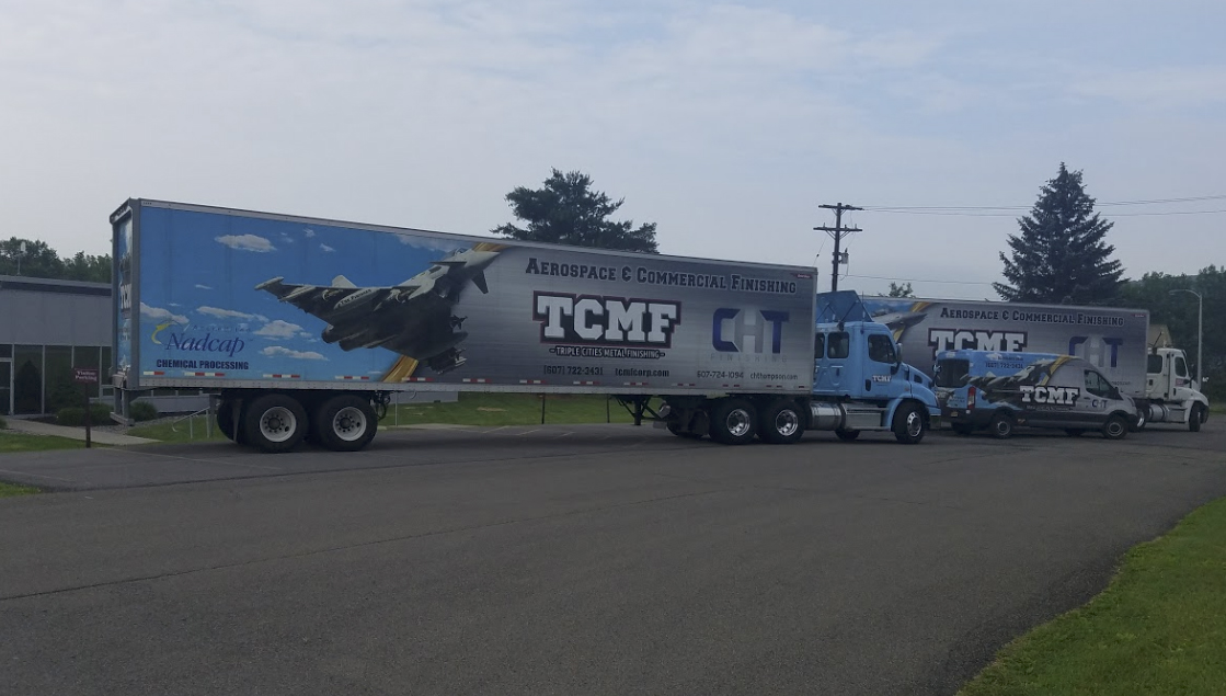 Two transport trucks and a van designed to advertise TCMF.