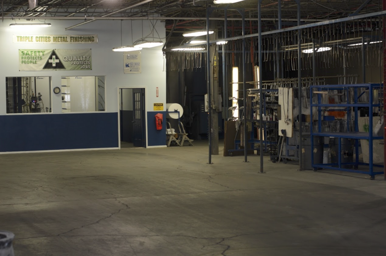 Large cement room with rows of drying hooks to hang freshly painted metal works from.