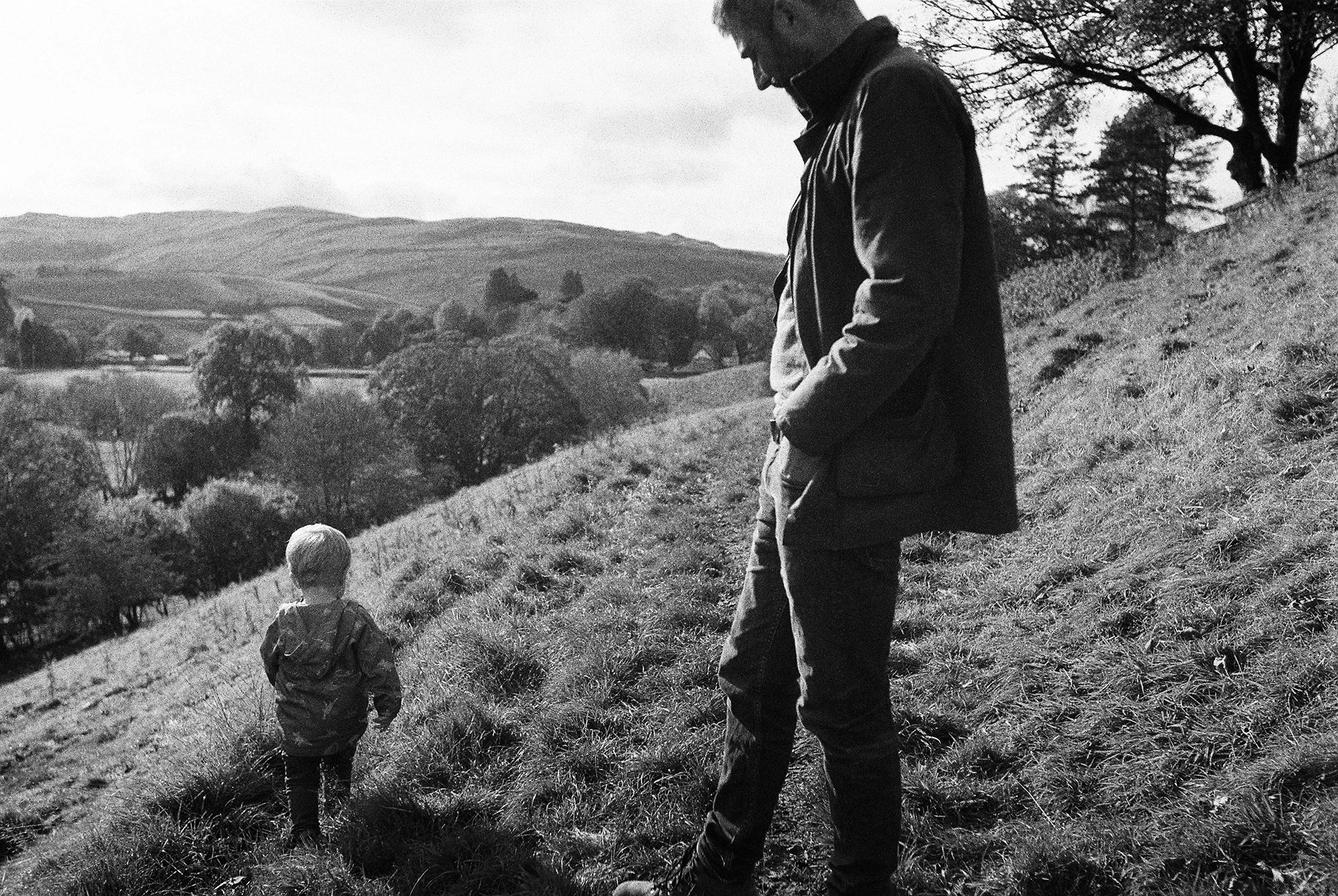 A dad looking at his son while he walks in the cumbrian countryside, photo by Molly Matcham