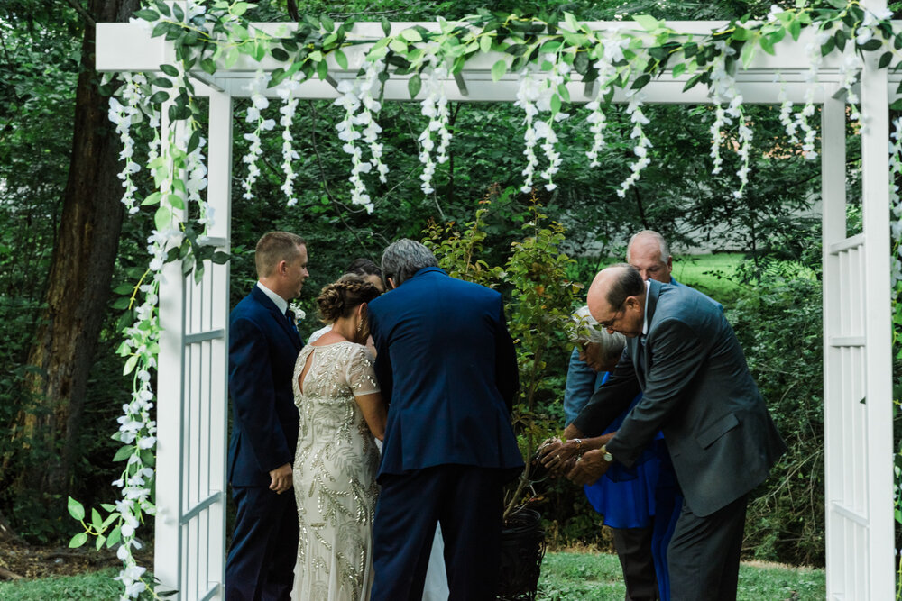  During the ceremony, both sets of parents and the bride and groom participated in a tree-planting ceremony. The parents added in dirt, the couple watered the tree and after the wedding, they’ll plant it at their home and watch it grow as they grow i