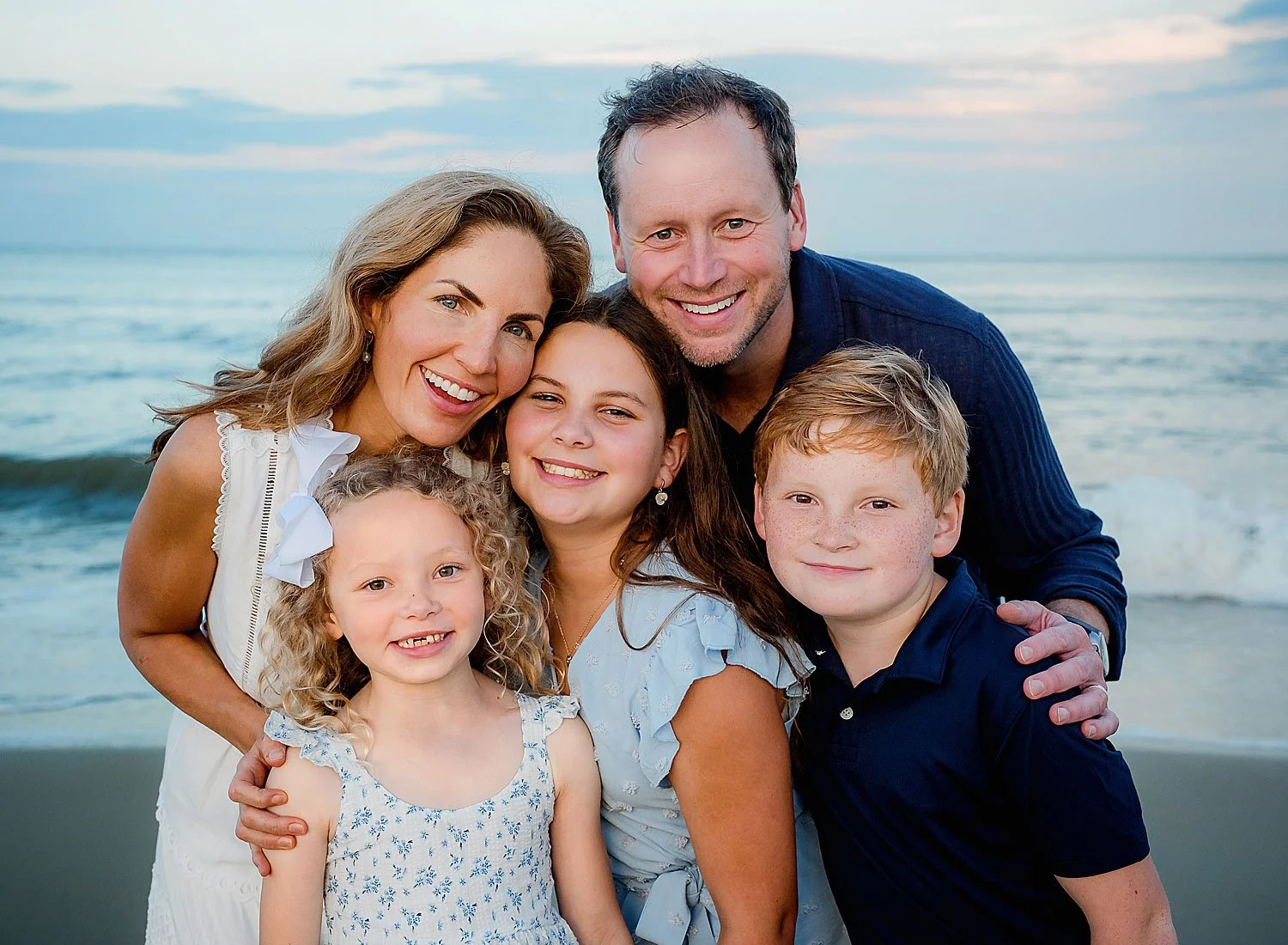 family poses by the ocean in Virginia Beach during photo shoot at sunset