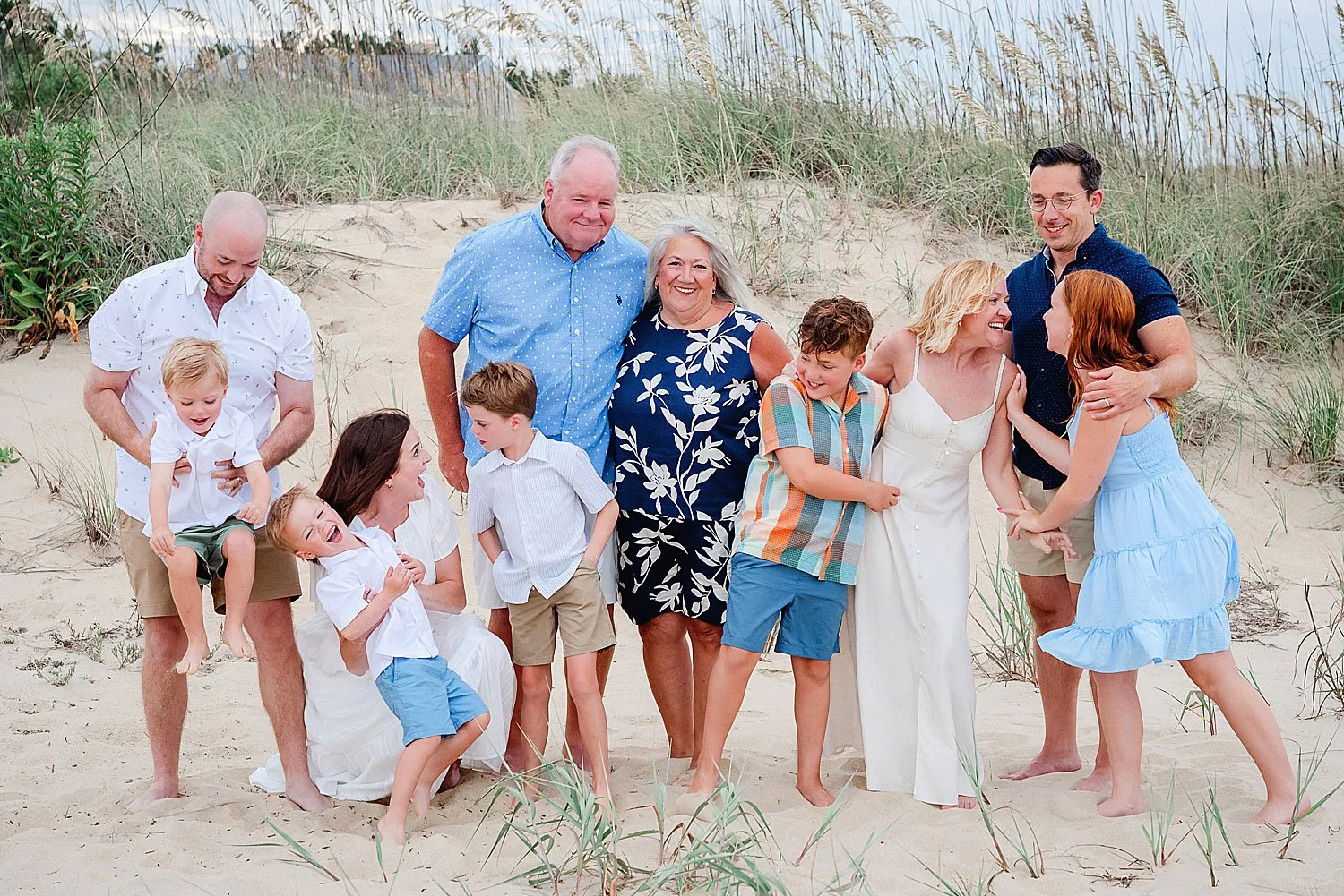 Sunset photo of grandparents, children, and grandchildren playing by the dunes in Sandbridge