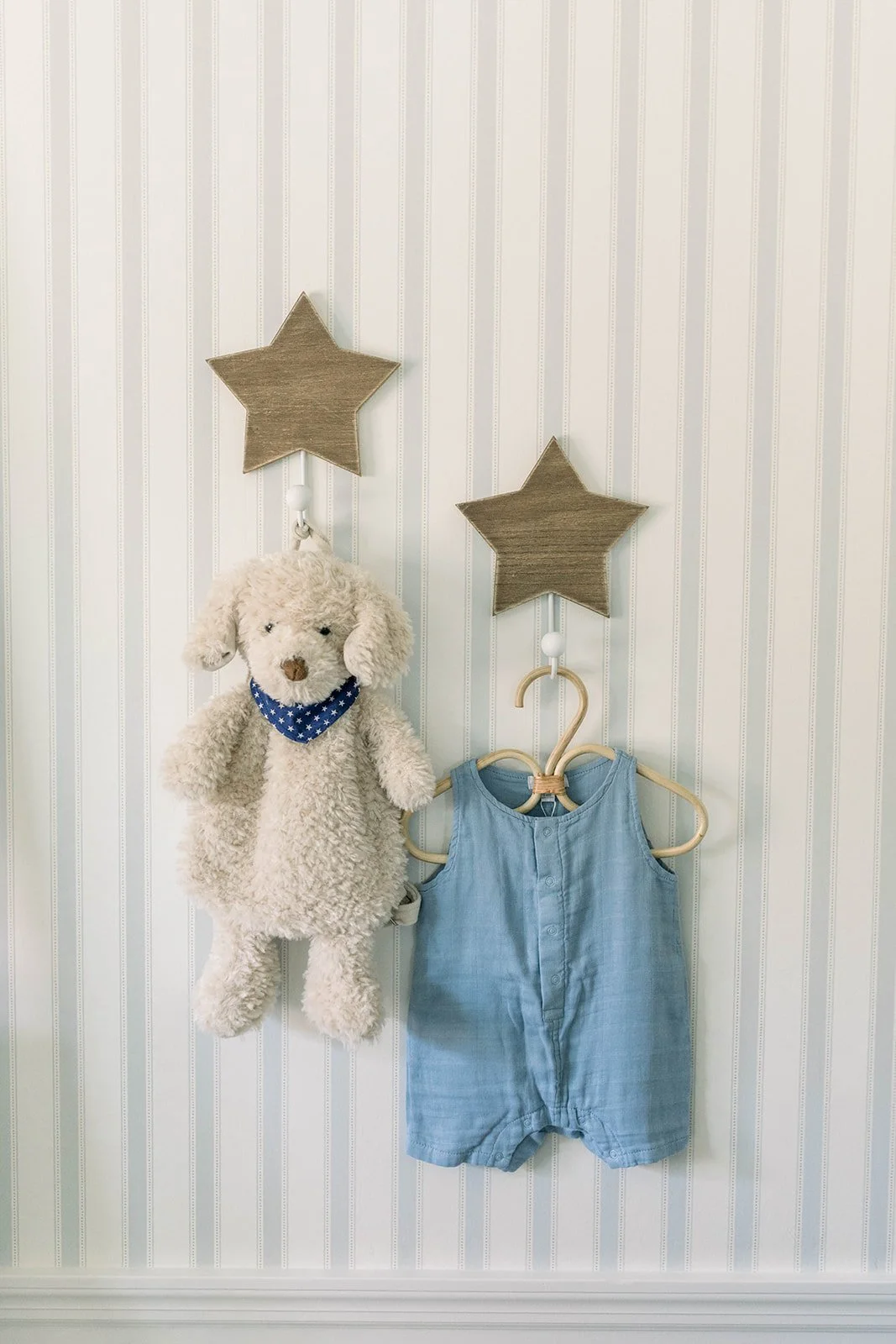 Toy stuffed dog and denim romper hang on star hooks in baby boy nursery