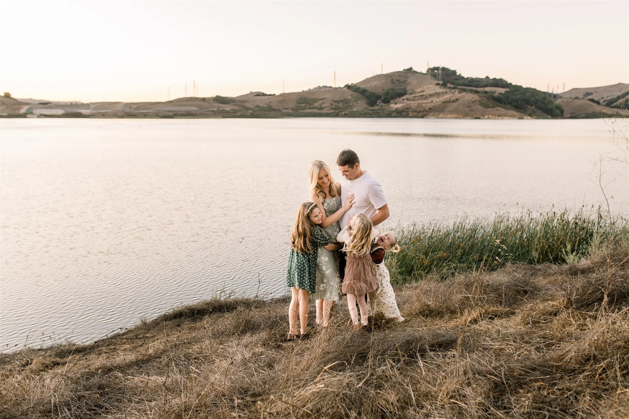 Family of five snuggles in front of a lake