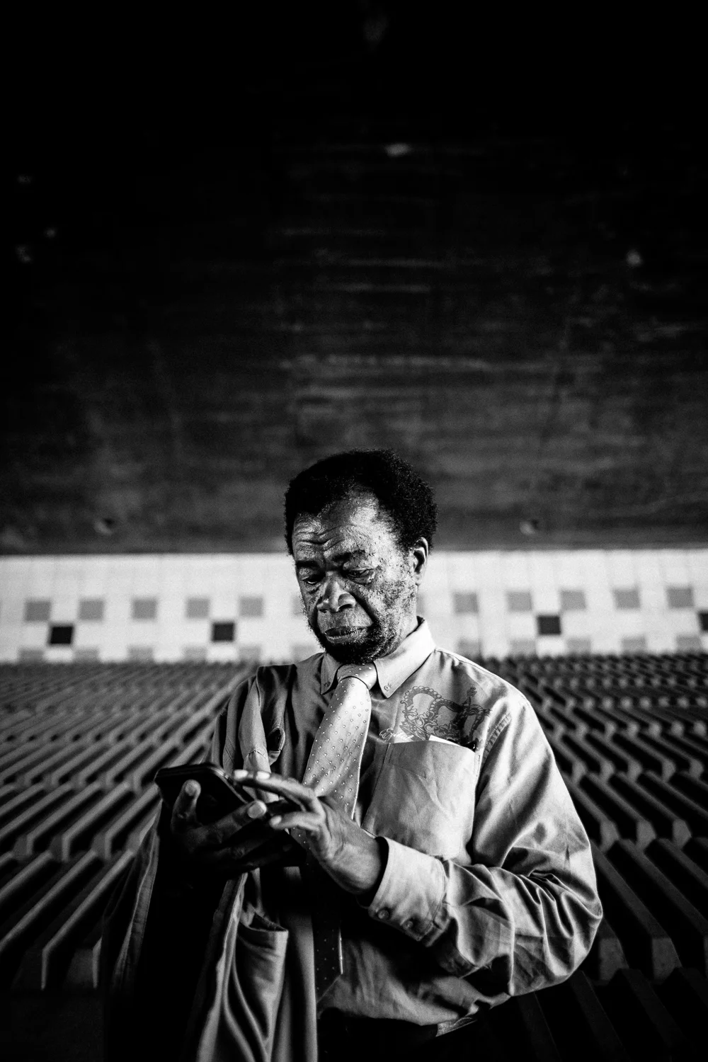 Moment Eight: The same scene, a slightly distinct angle, an entirely different moment. Commuter. Not the slightest connotation of disorder, poverty, homelessness, or unhappiness. Here, more than any other, Johnny appears to be the medical expert he is. A kind soul from Sierra Leone waiting for the bus. Sharing with a stranger, pictures of his three adult children, one of which recently graduated from the University of San Diego. More than any other moment, we can conceive of this man being a world traveler, cultured and erudite.