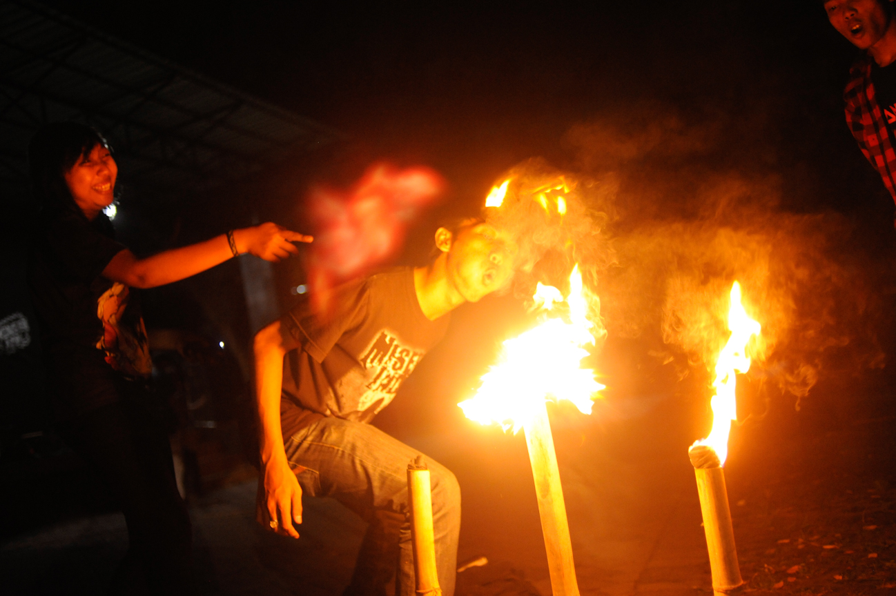 One of the students helping setup for the charity concert at Universitas Islam Negeri tries, unsuccessfully, to blowout the bamboo torches created, specifically for the event, just hours before at the Rayon.