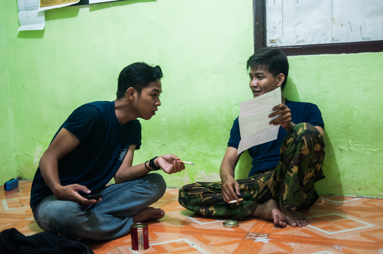 Hasan shows Navic the formal PMII announcement of a demonstration which is to be held in protest of strict educational regulations that will limit the amount of years students may take between secondary school and enrollment in a university. Though this affects none of the PMII members directly, the proposed changes will make it far more difficult for those students who must spend several years working before saving enough to pay for classes, to get a university education.