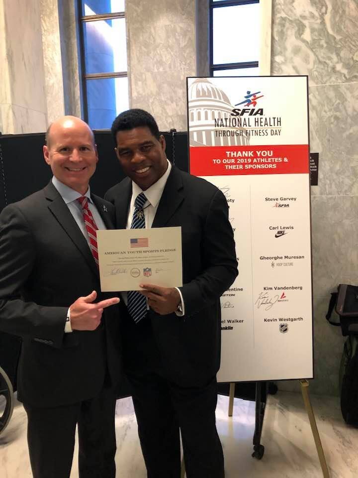  Executive Director, Clay Walker (L) holds the American Youth Sports Pledge with Herschel Walker (R). 