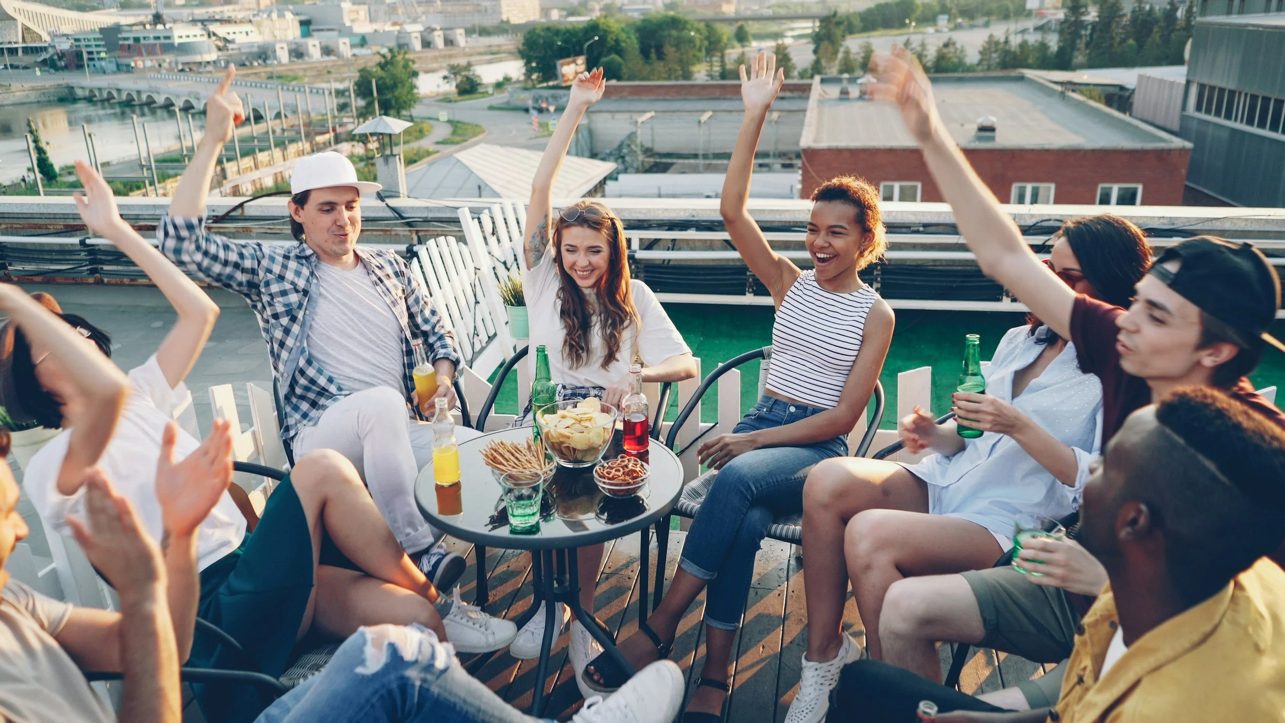 Group of adults sitting in a circle, raising their hands and smiling.