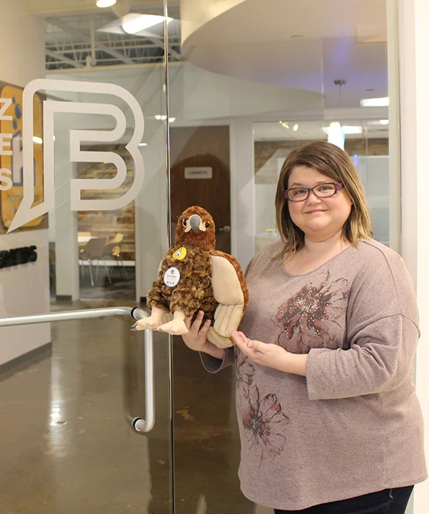 Anna standing in front of Buzz Franchise Brands office with Buzzy