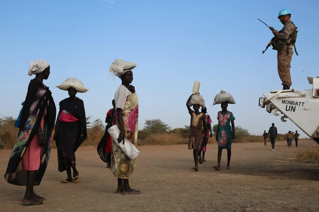 A U.N. peacekeeper stands on watch as South Sudanese women head to a protection camp in Bentiu, South Sudan, in December 2017.