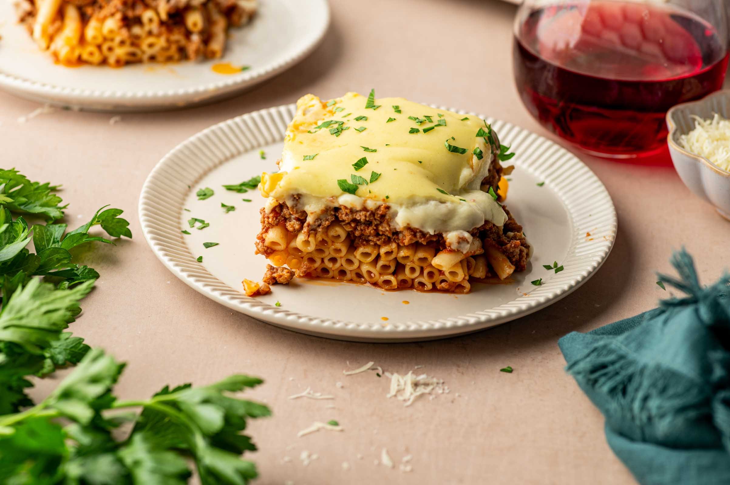 A serving of pastitsio on a white plate garnished with parsley