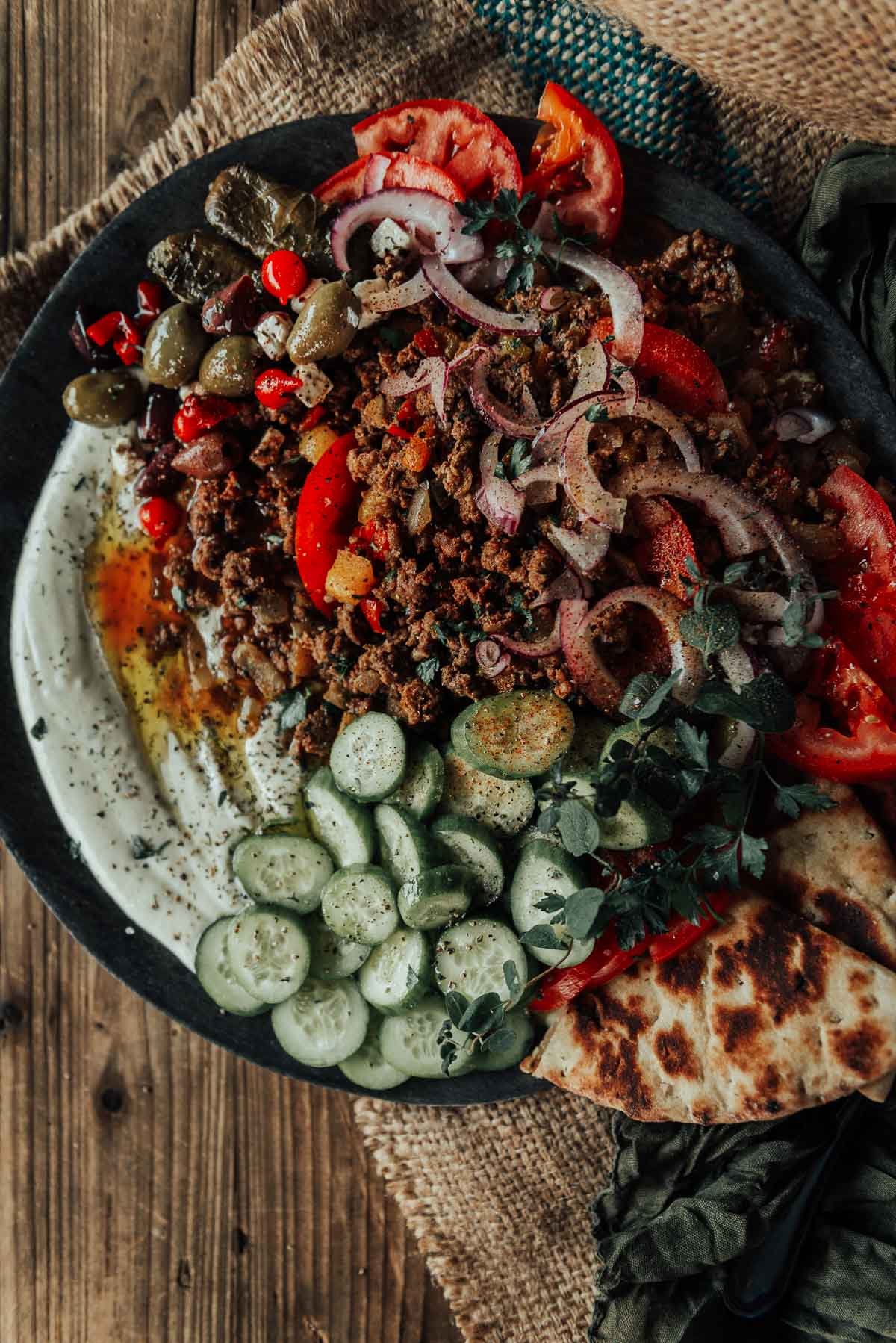 Greek ground lamb served with whipped ricotta, sliced cucumbers, herbs, and naan.