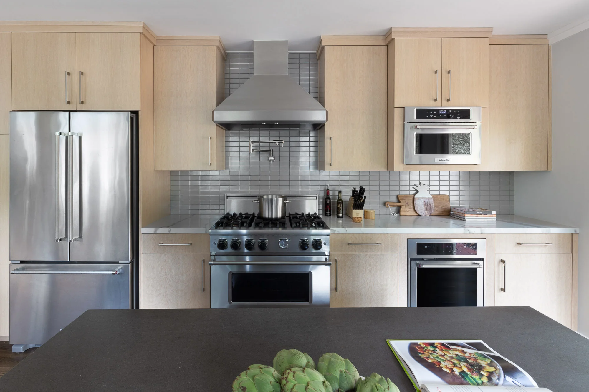 Contemporary kitchen in Lafayette, CA with stainless steel appliances, white oak cabinetry, Calacatta Quartz counter and Ann Sacks pearl shimmer mosaic tile.