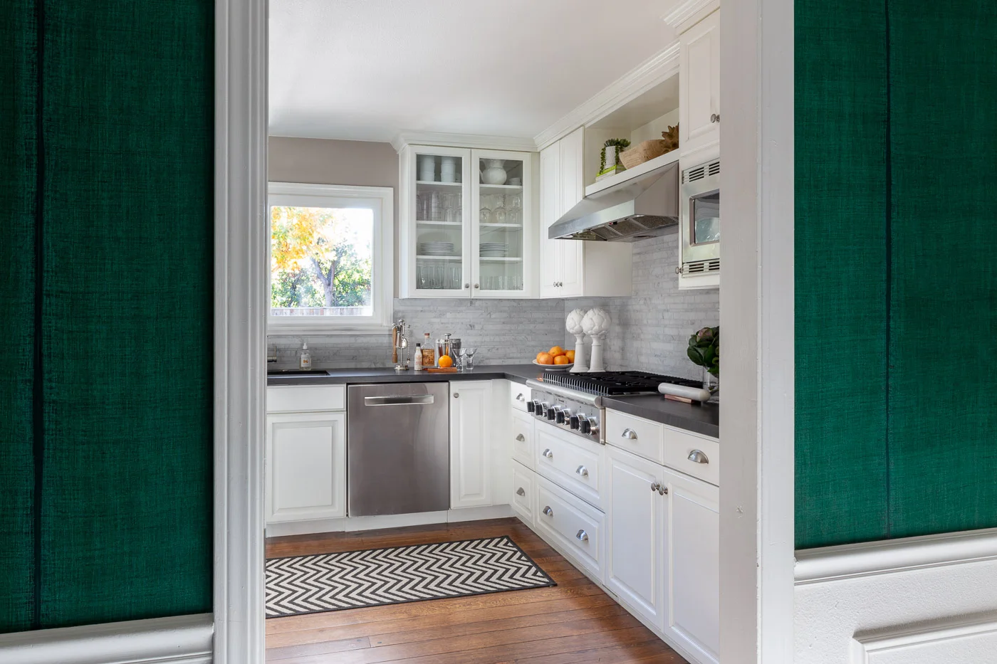 Green Elitis wallpaper as you enter this Danville, CA transitional kitchen with a leather finish Basaltina counter and random strip Carrara backsplash