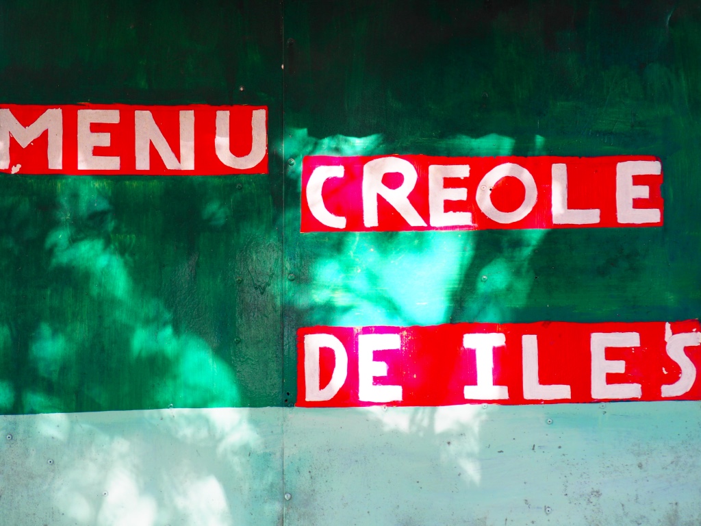 A food stall in Grand Bai proclaims its creole menu in bright kitschy fashion. Hawker stalls like this dot the island selling everything from samosas to fresh fruit to ice cream.