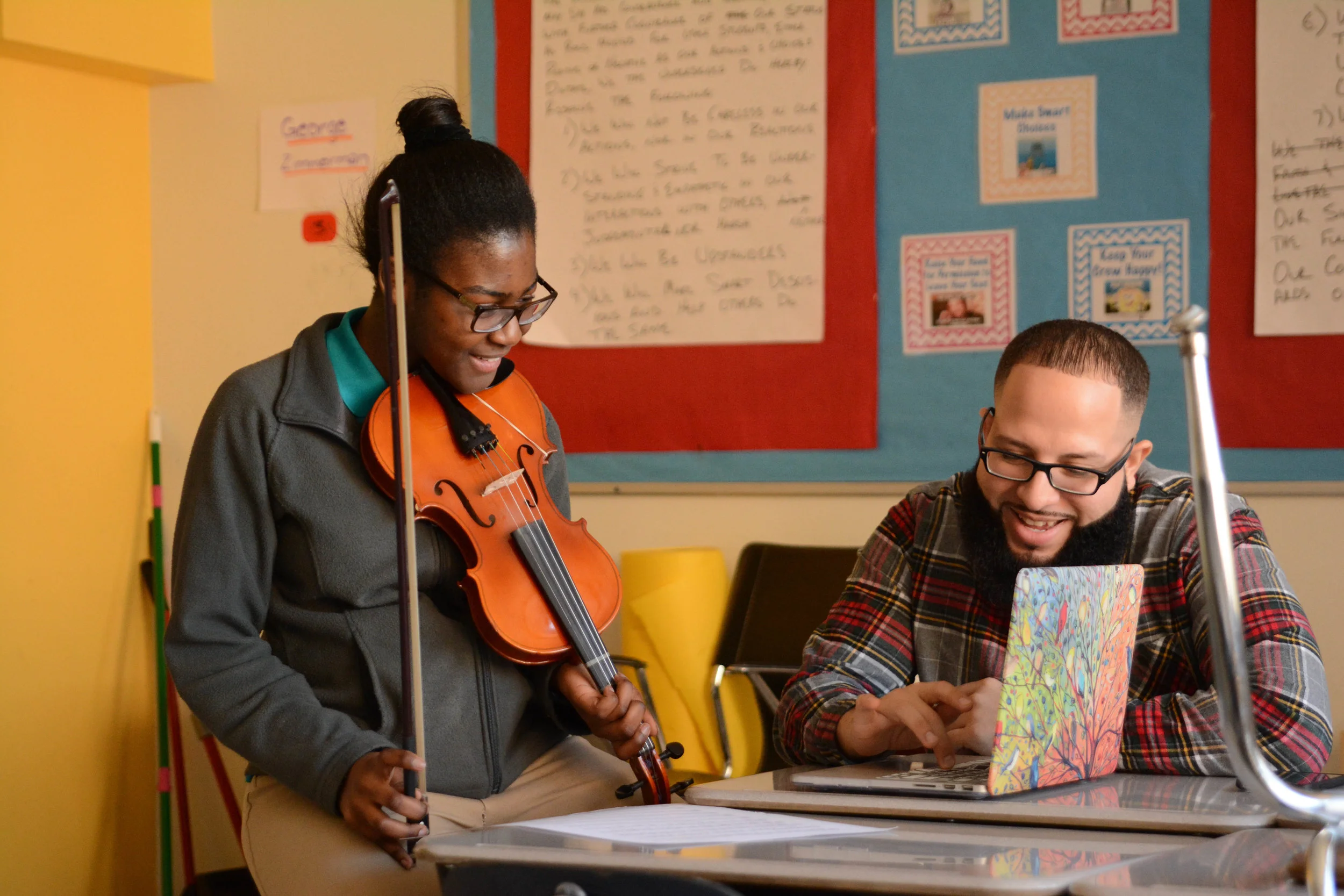Classroom support assistant Mr. Santiago works with a student to record her playing her original composition.