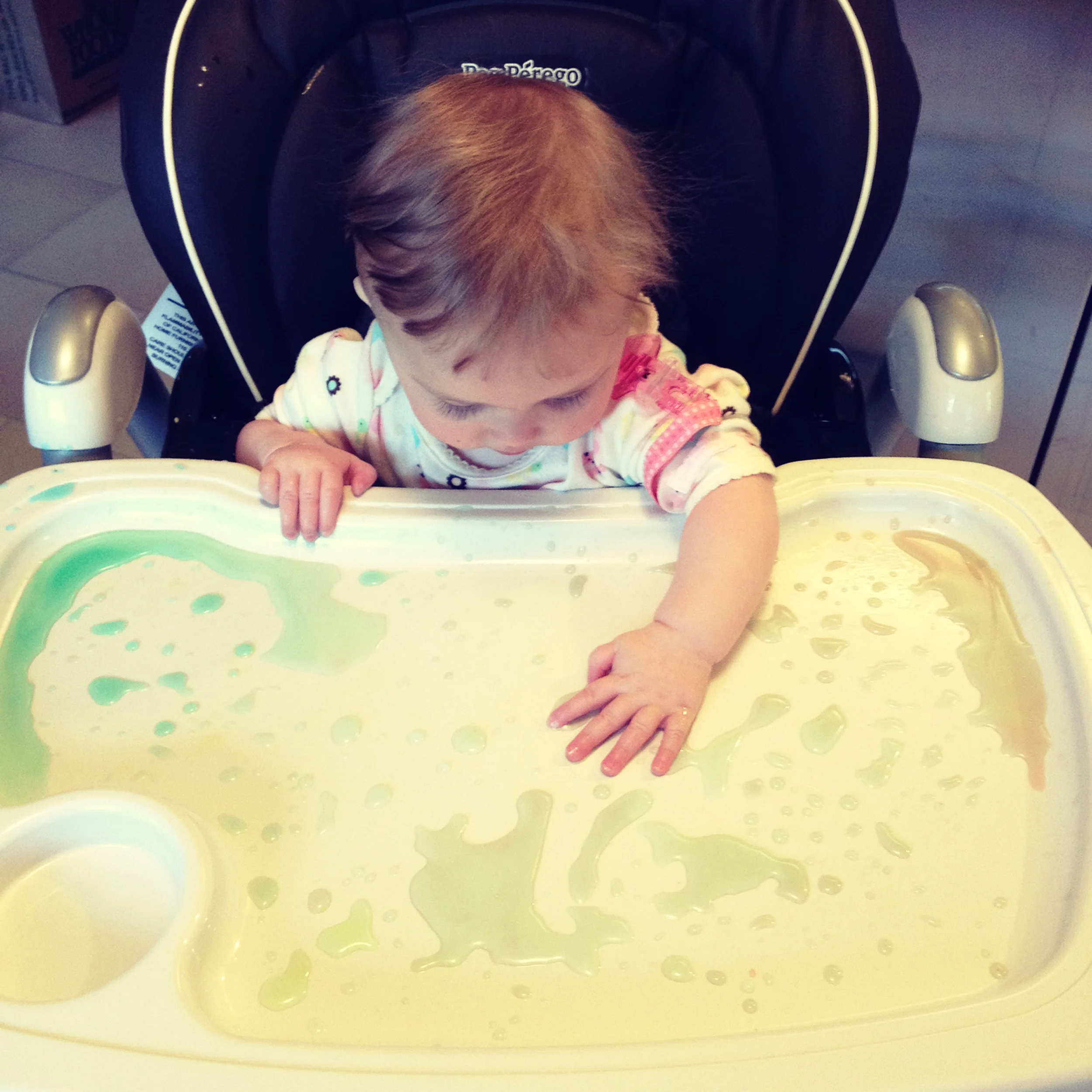 My daughter exploring watercolor droplets on her tray, age 8 months