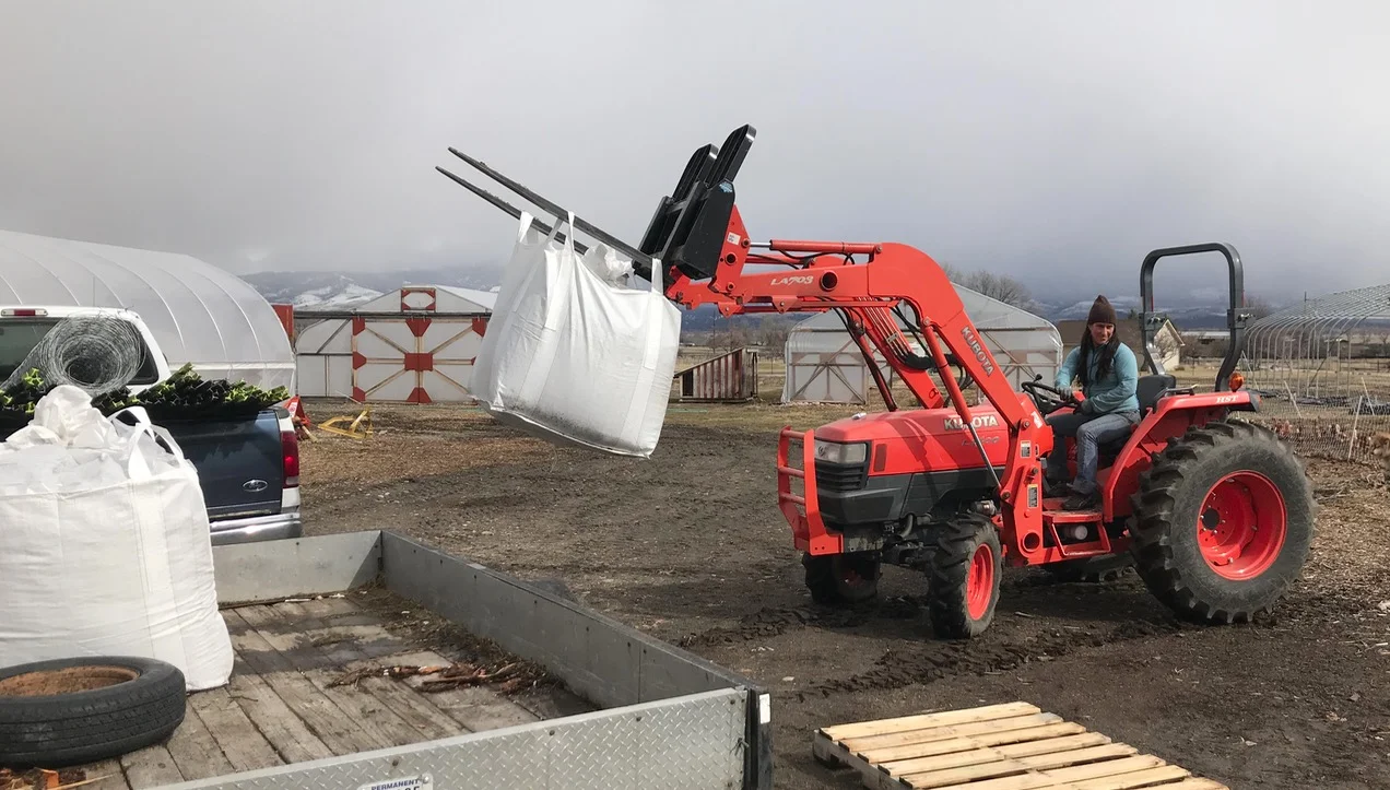 Mary unloading totes of organic potting soil with one of our favorite tools, purchased with our first real bank loan in 2017.