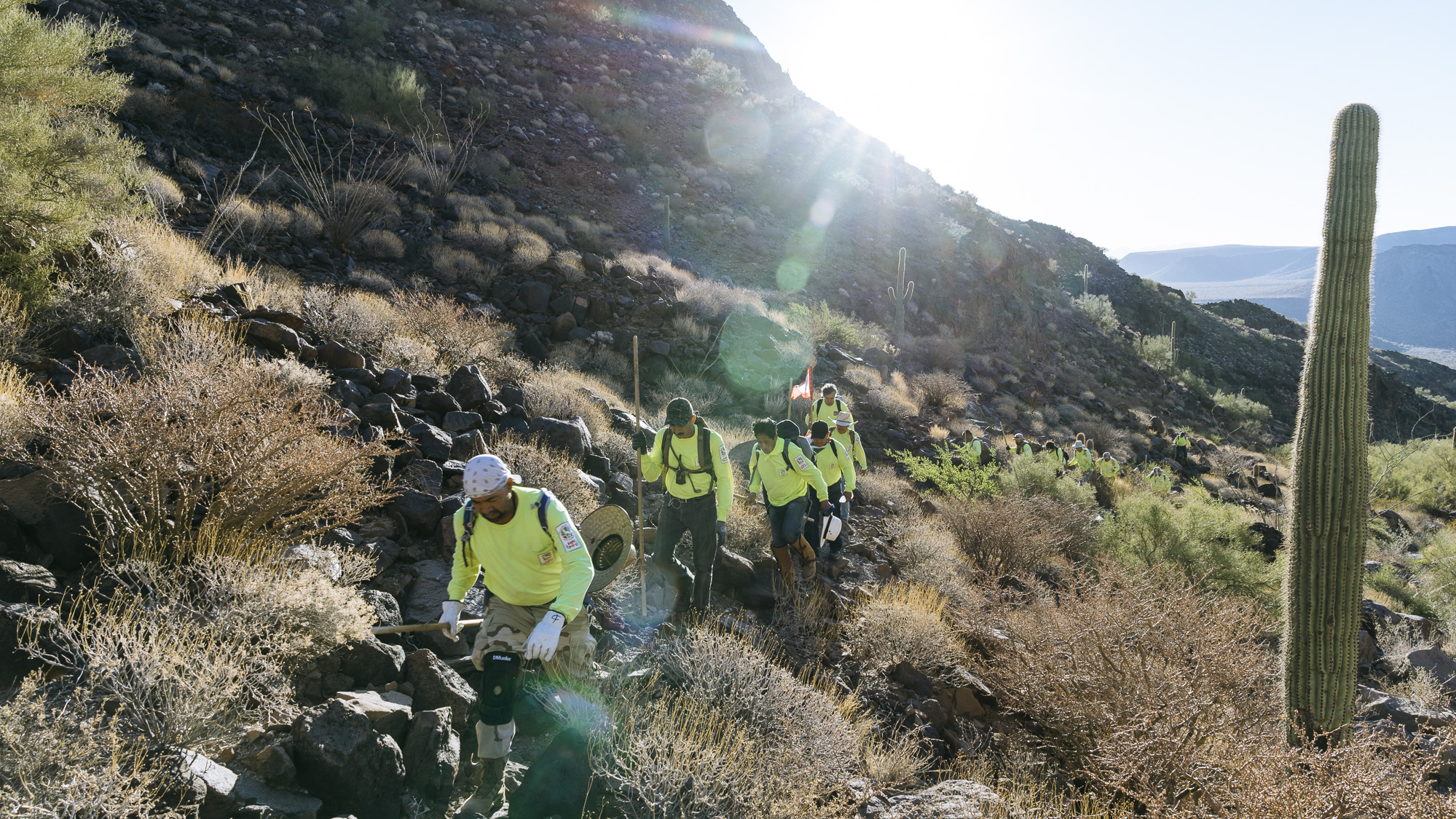  IMAGE CAPTION:  Members of Aguilas Del Desierto crest a hill in the Cabeza Prieta National Wildlife Refuge outside of Ajo, Arizona. For migrants crossing into the United States through this Sonoran Desert route the journey often takes 7-10 days with