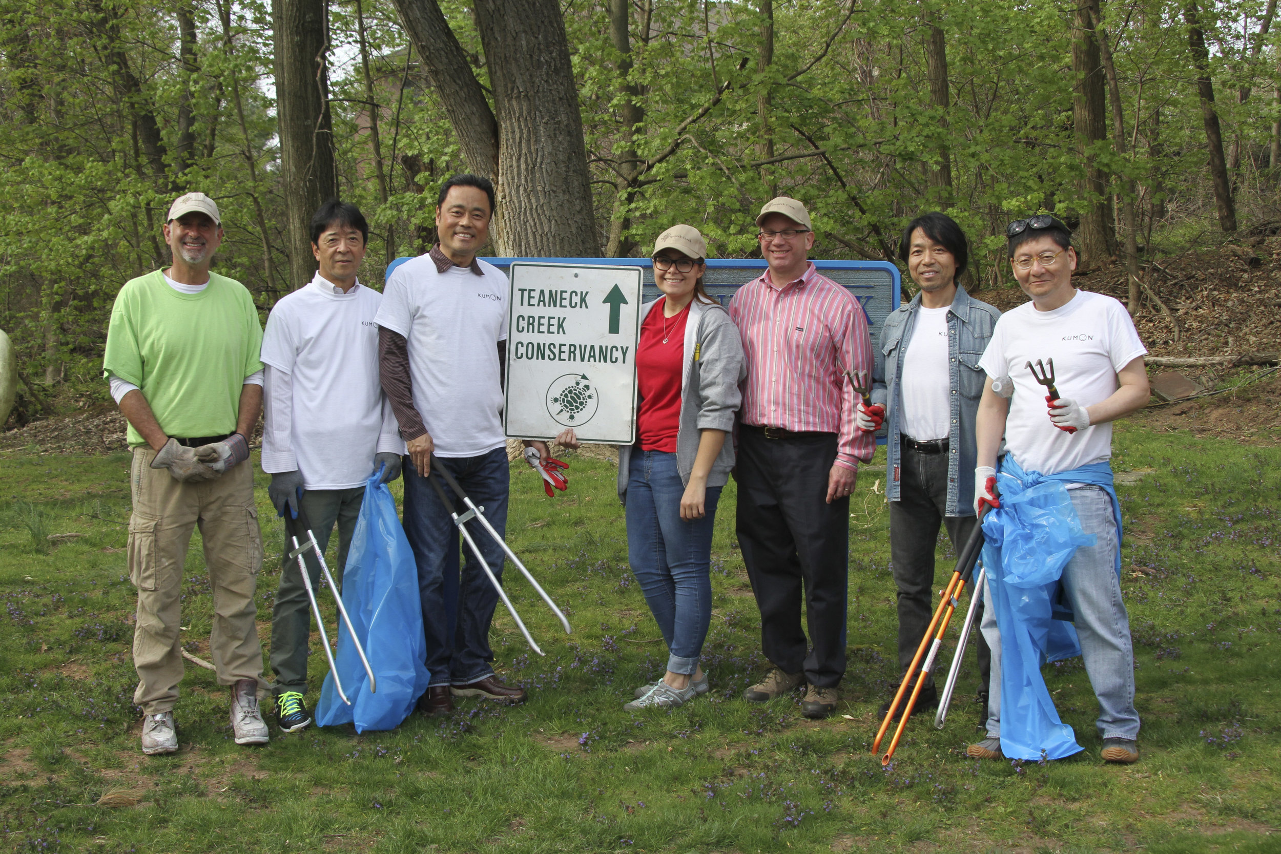  small group of dedicated volunteers with trash pick up tools and blue trash bags 