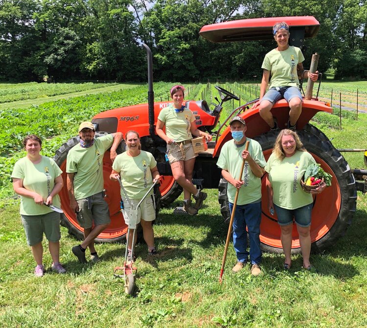 Team of farmers and farmhands by orange tractor
