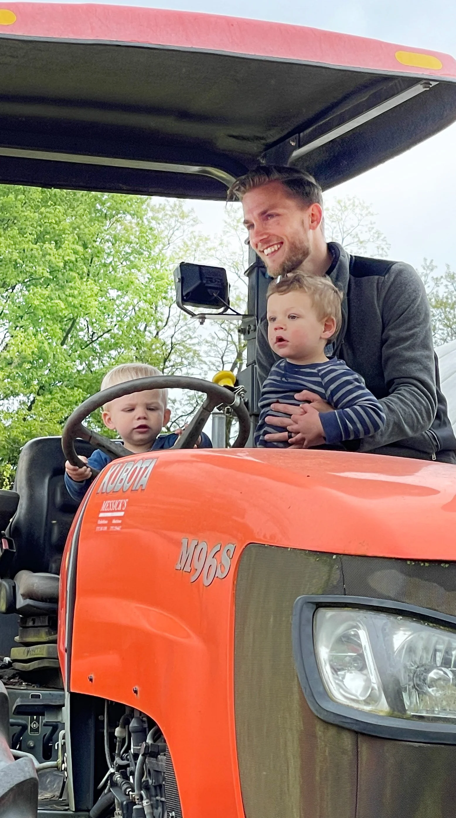 Father with two young children on big orange tractor