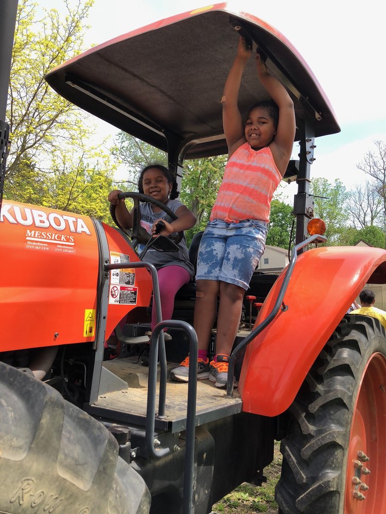 Two children in the driver's seat of the big orange tractor