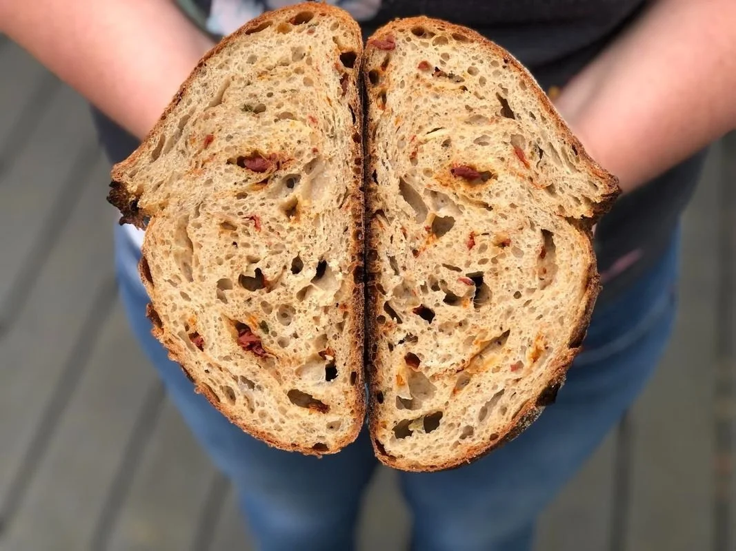 A woman displaying a loaf of bread cut in half.